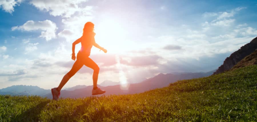 Woman running on hill during sunset