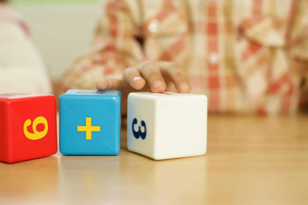 Blocks with numbers and child holding hand above one