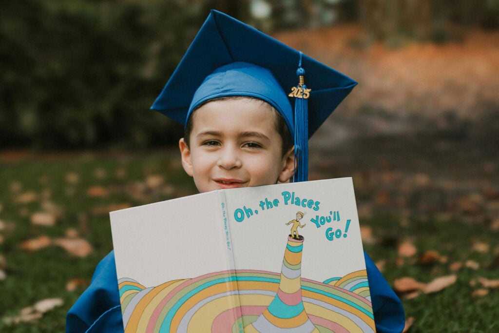 Young boy in graduation cap reading Oh the Places You'll Go