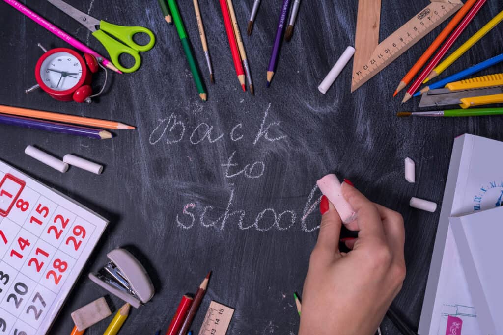 Back to school written on a chalk board with school supplies surrounding it